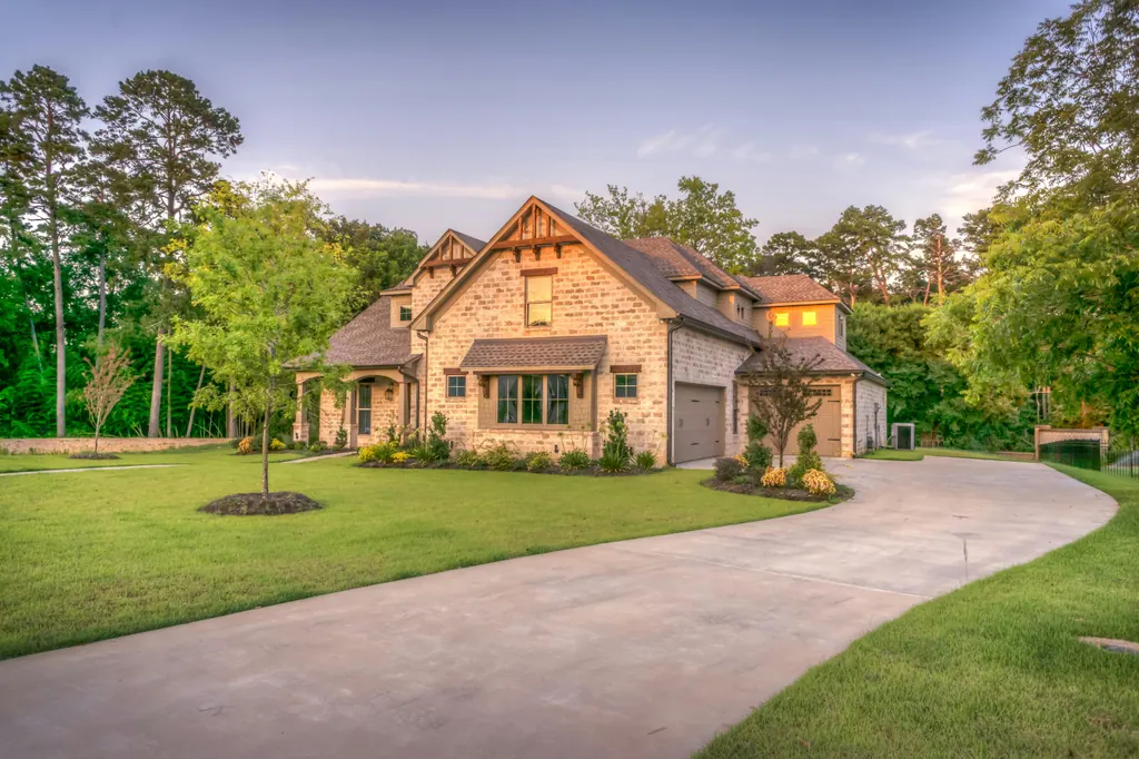 Brick home with a manicured lawn and curved driveway at golden hour