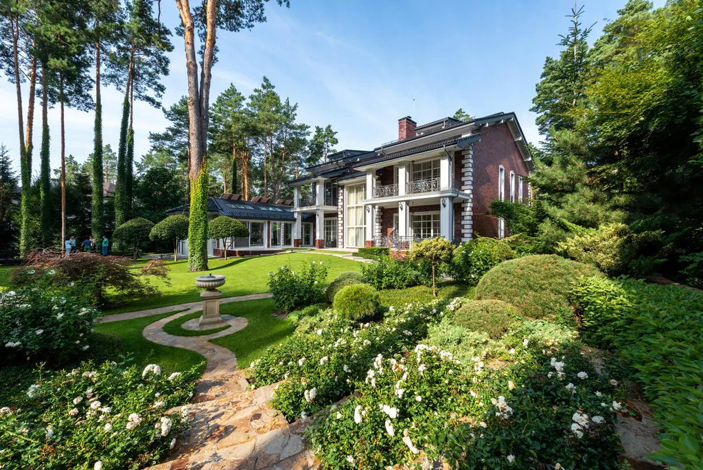 Sweeping manicured front lawn with mature pines and shaped hedges