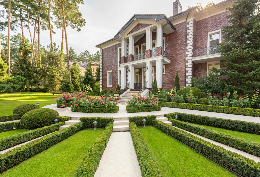 Manicured front lawn with stone walkway and formal trimmed hedges