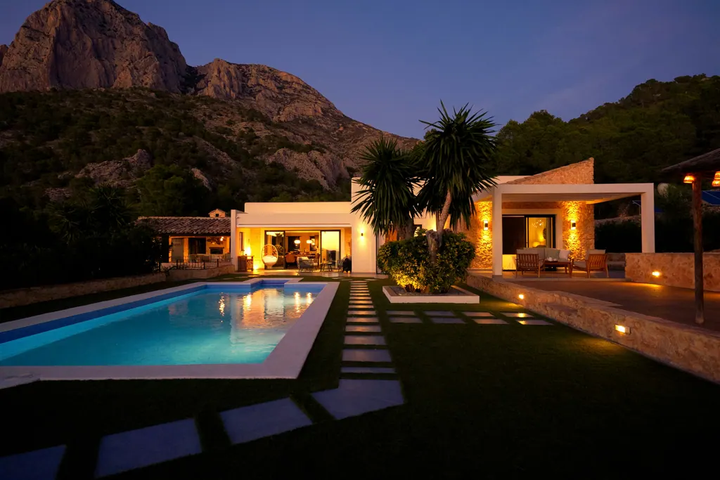 Landscape lighting illuminating a stepping-stone path beside a pool at dusk