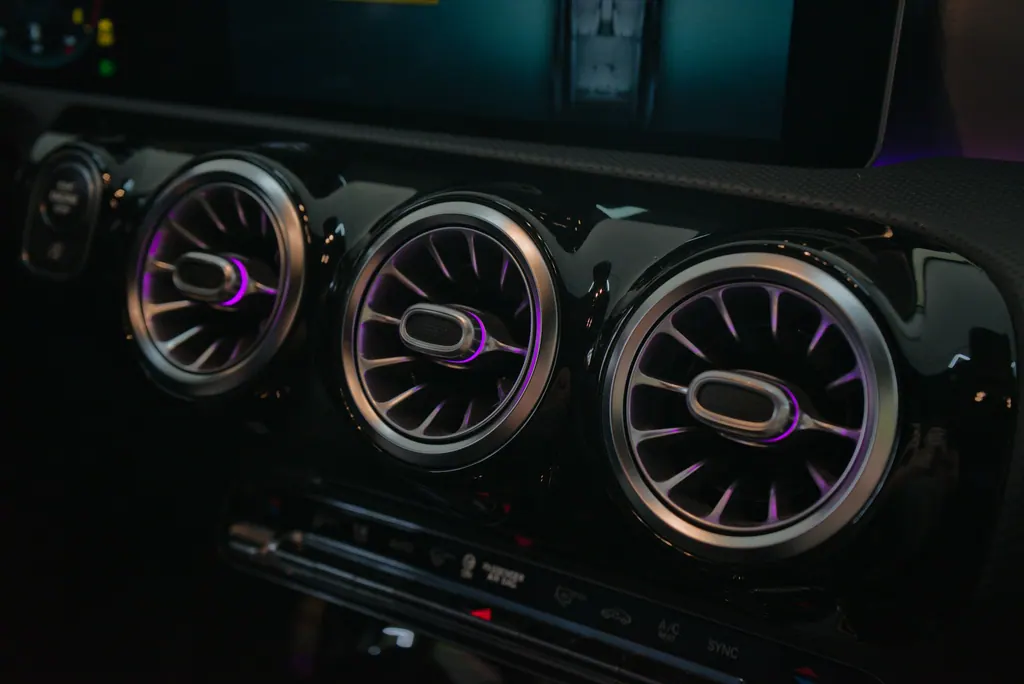 Illuminated turbine-style dashboard air vents above a climate-control panel with the A/C button visible