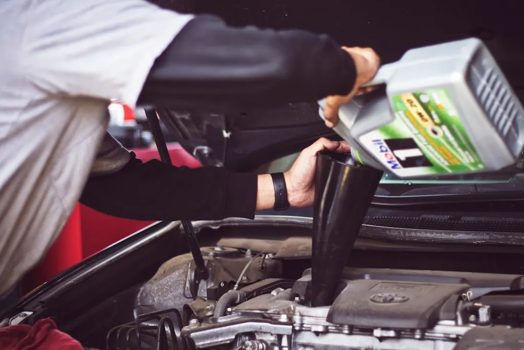 Mechanic adding fresh motor oil during an oil change service