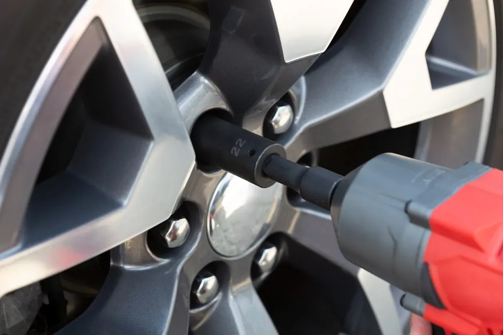 Impact wrench tightening lug nuts on an alloy wheel inside the shop